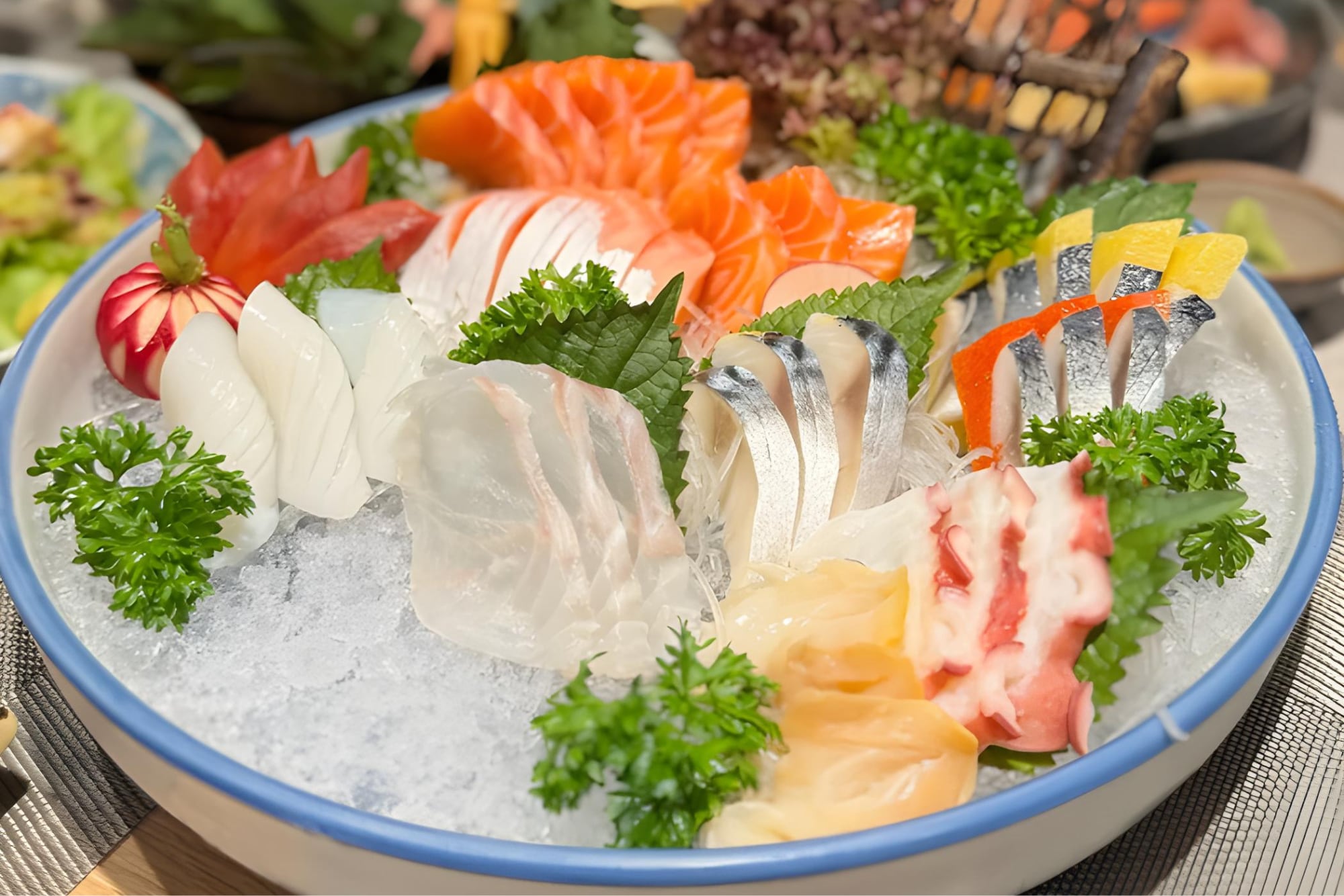 Mỗi lát cá được thái mỏng đều, xếp gọn gàng theo từng loại - nổi bật là cá hồi cam óng, cá trích bạc, bạch tuộc, cá trắng
